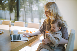 Femme en télétravail qui porte un bébé dans ses bras